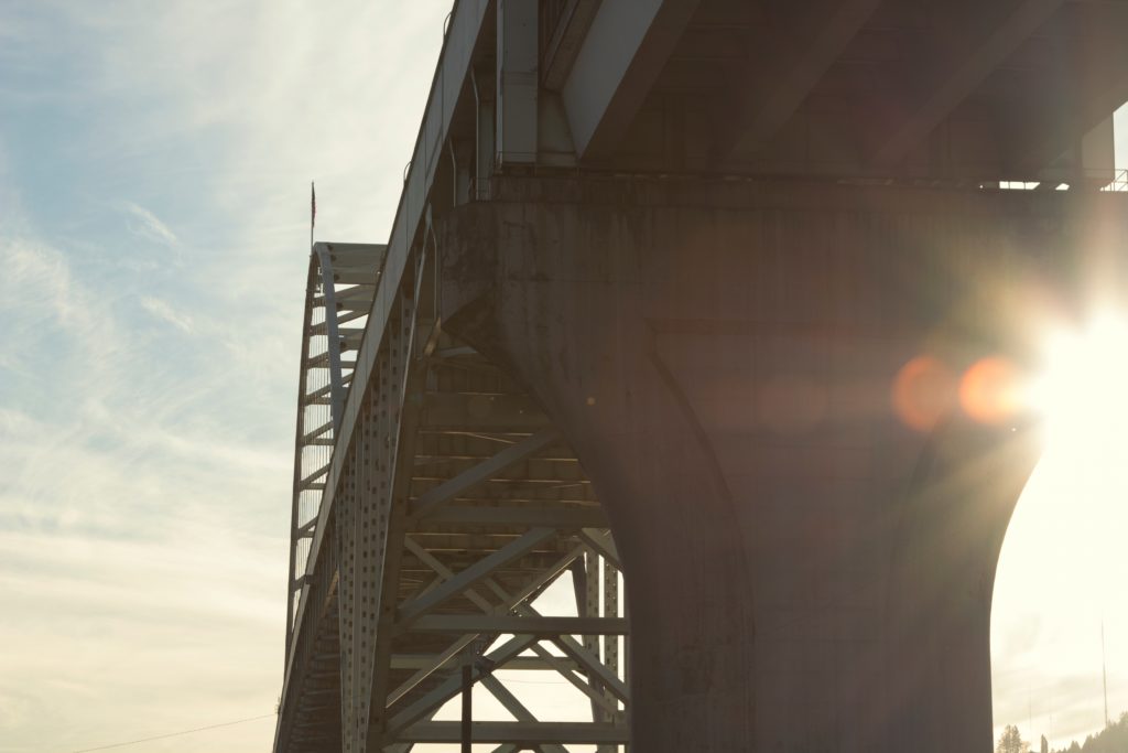 Sun shining on a highway bridge viewed from a low angle.