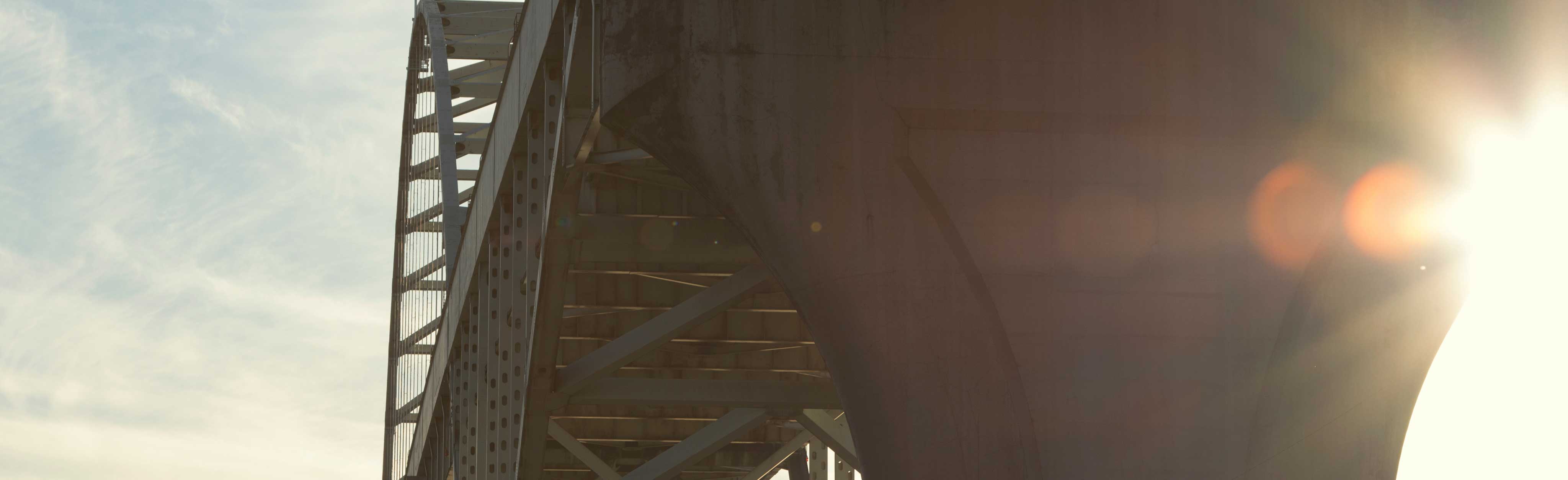 A photo of the sun shining on a highway bridge viewed from a low angle. The image shows a lot of lens glare.